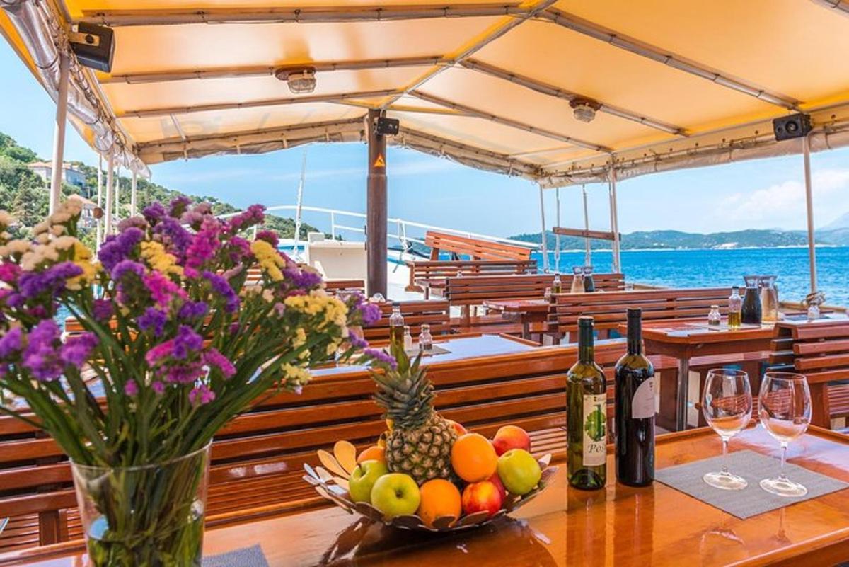 un tavolo con frutta e bottiglie di vino su una barca