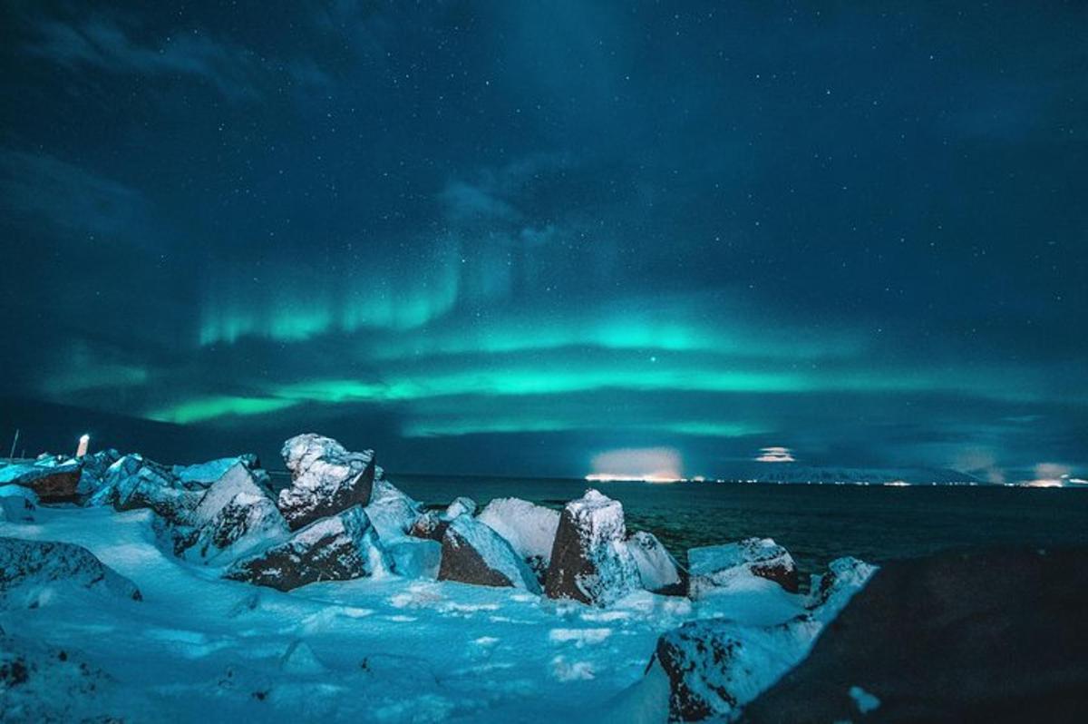 Un grupo de rocas en la nieve bajo la aurora boreal.