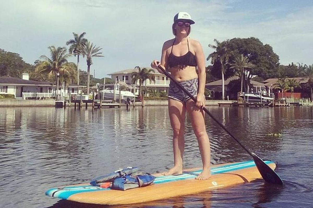 žena stojící na paddleboardu ve vodě