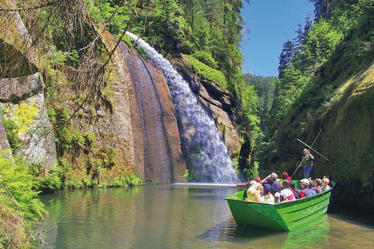 een groep mensen in een groene boot voor een waterval