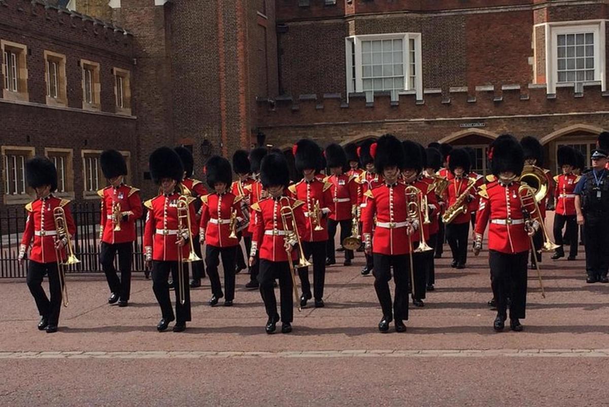 a marching band in red uniforms walking in front of a building