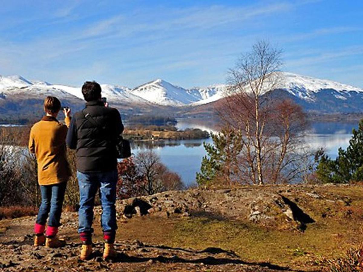 two people standing on top of a hill looking at a lake
