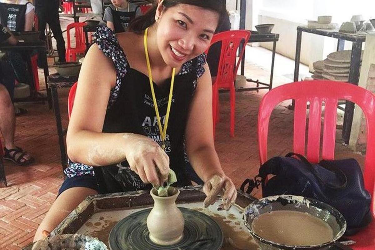 a woman is making a vase on a table
