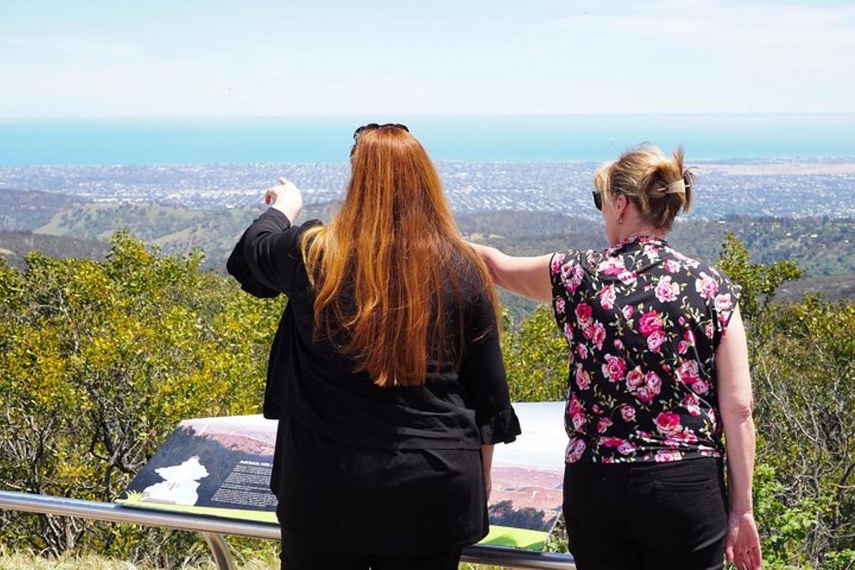 dua wanita berdiri di atas bukit sambil memandangi kota