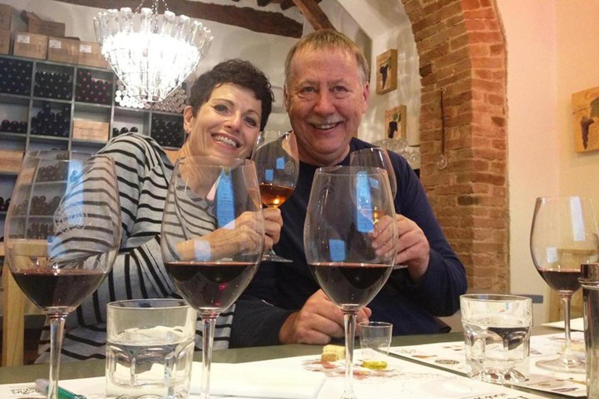 moški in ženska sedita za mizo z vinskimi kozarci