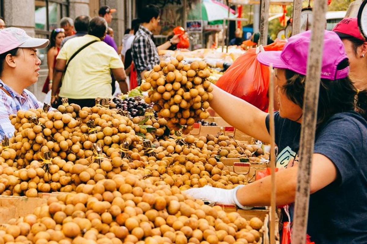 a woman standing next to a pile of oranges in a market
