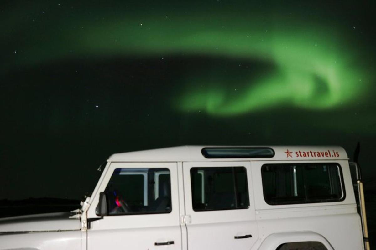 un furgone bianco parcheggiato sotto l'aurora boreale verde