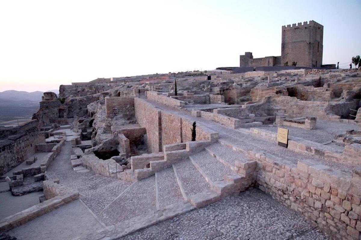 Unas ruinas antiguas con un castillo al fondo