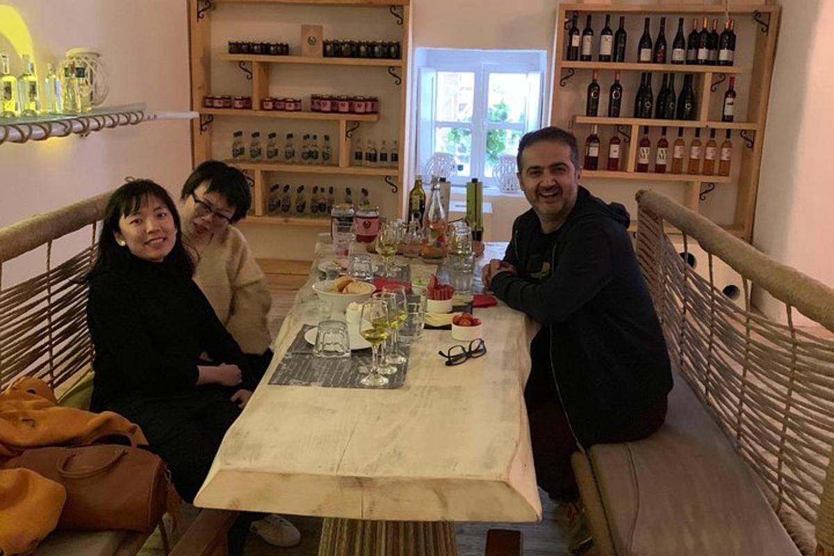 un grup de persones assegudes al voltant d'una taula amb ampolles de vi