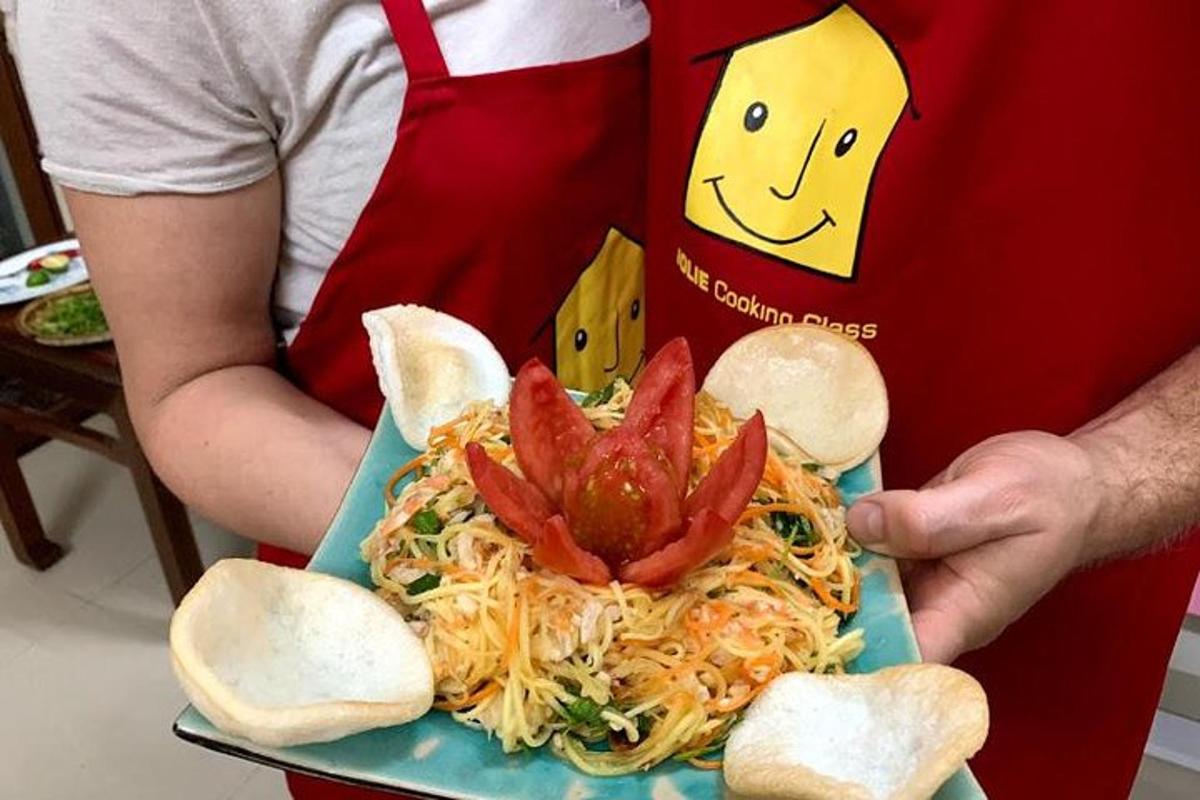 cilvēks tur rokās šķīvi ar spageti, uz kura uzliktas garneles