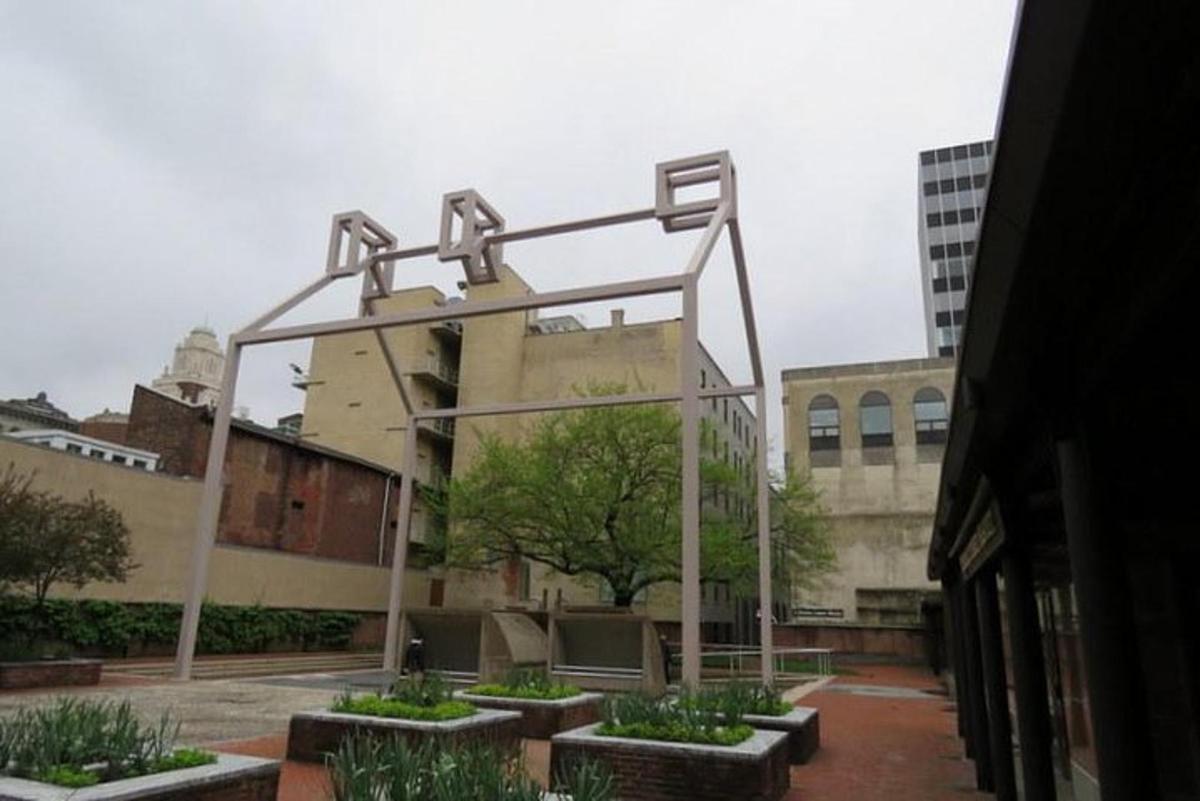 una grande struttura metallica con panchine di fronte a un edificio