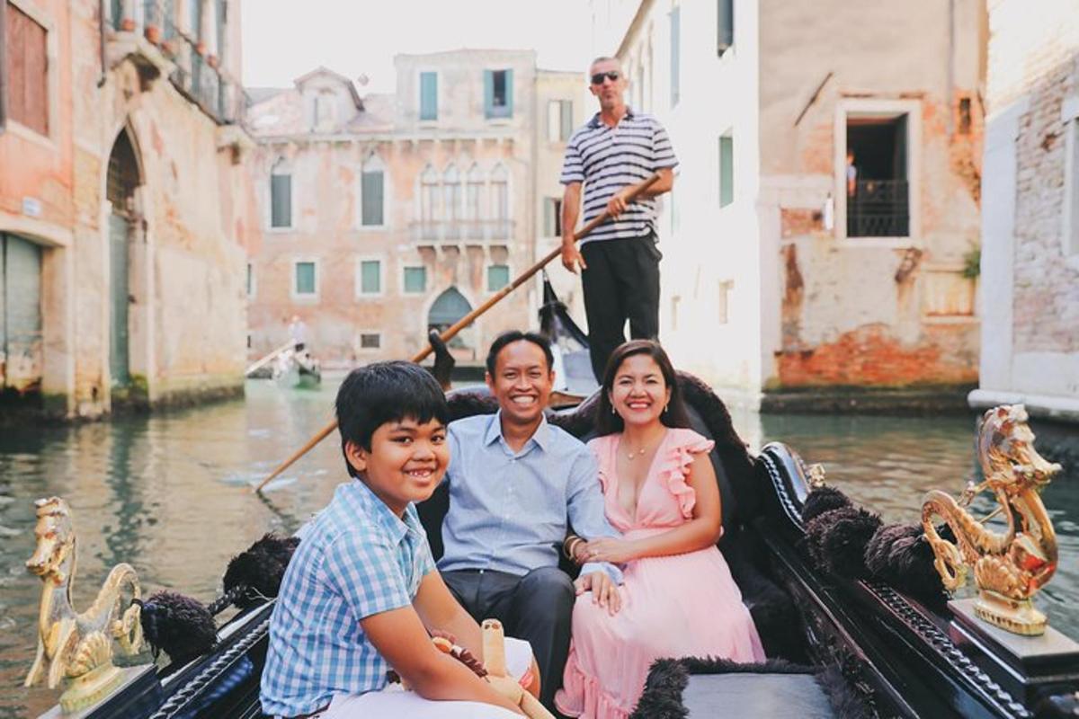 sebuah keluarga yang duduk di dalam gondola di atas terusan
