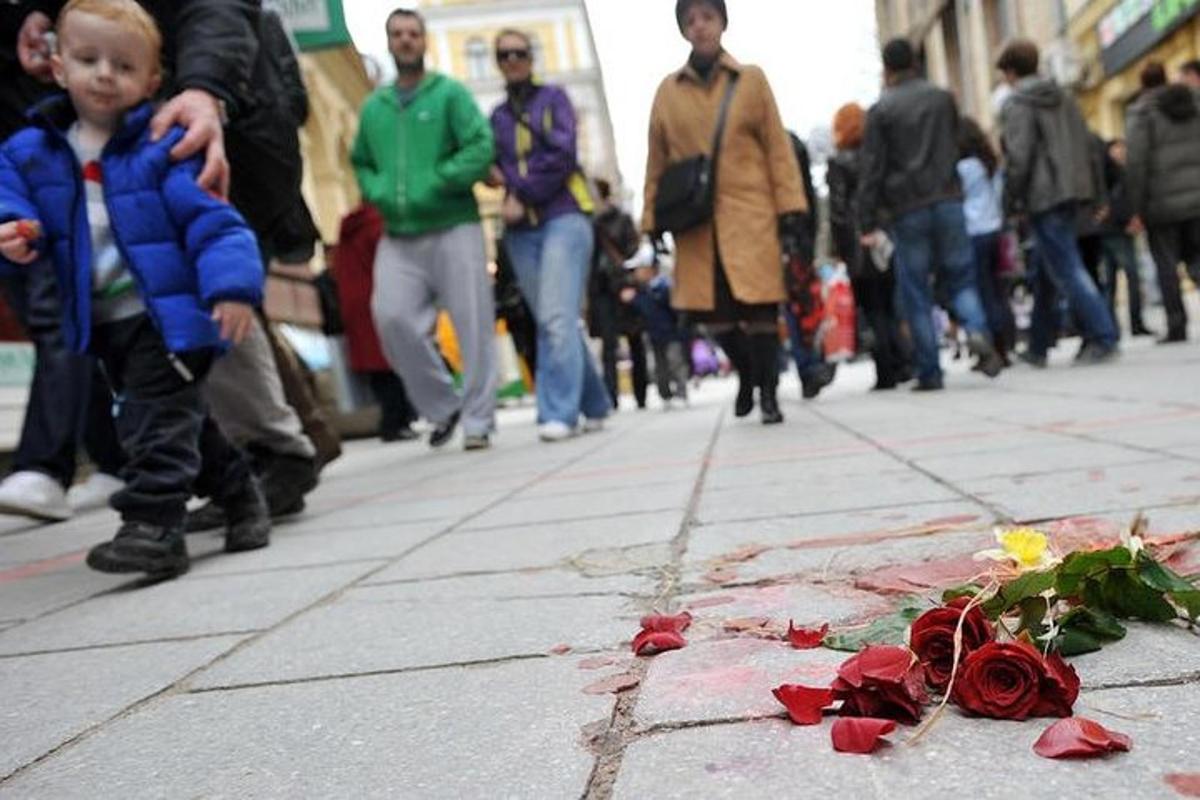 a boy is looking at a pile of roses on a sidewalk