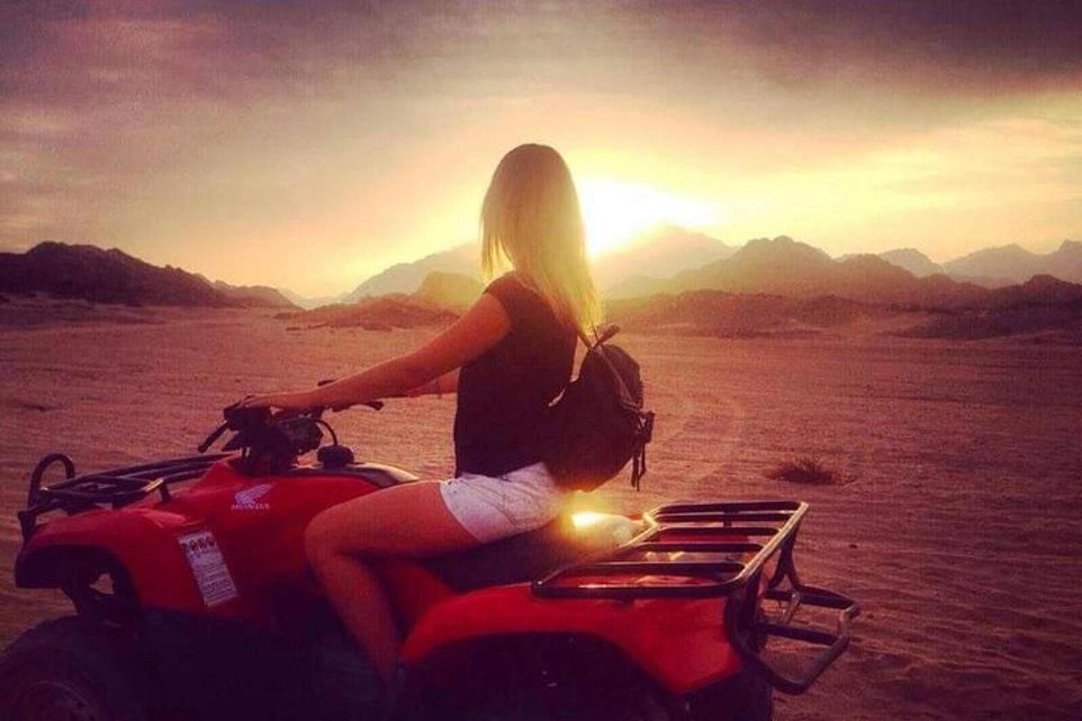 uma mulher sentada em uma motocicleta no deserto