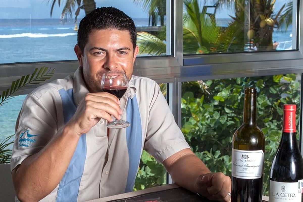 en mand sidder ved et bord og drikker et glas vin
