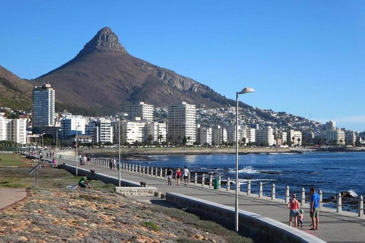 a group of people walking along a beach with a mountain