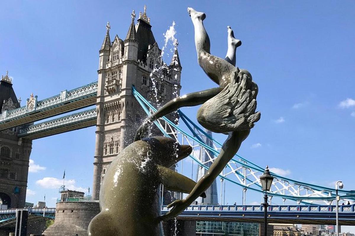 eine Statue einer Frau und zwei Schwäne vor einer Brücke