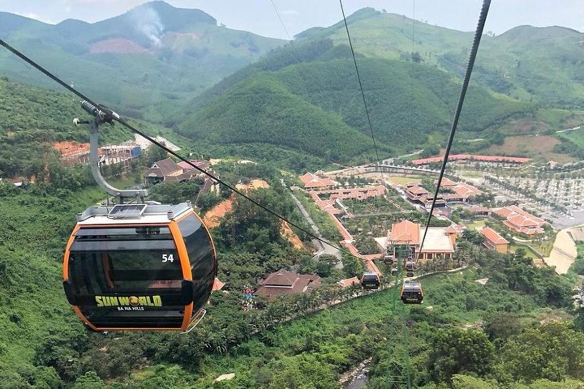 an orange cable car flying over a mountain