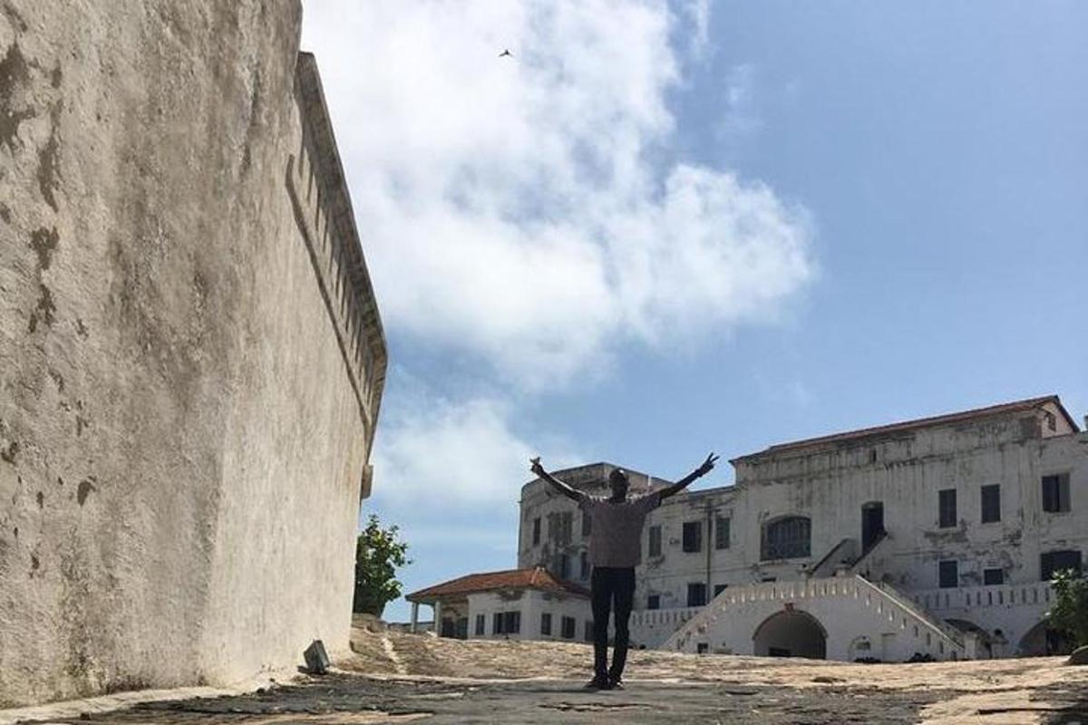 Un hombre parado frente a un edificio con los brazos extendidos.