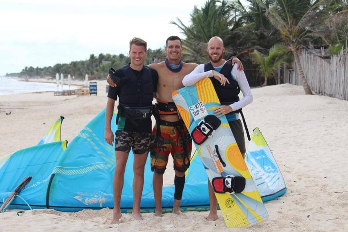 three men standing on the beach with their surfboards