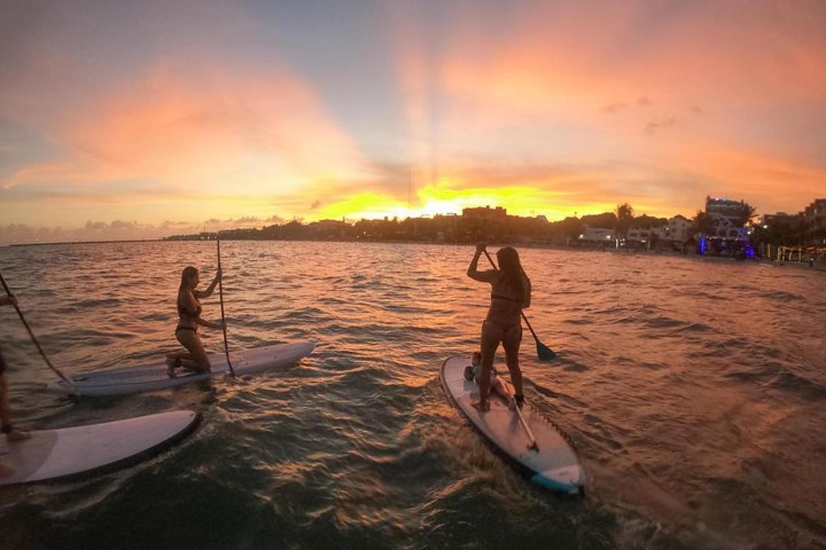 two people on paddle boards in the water at sunset