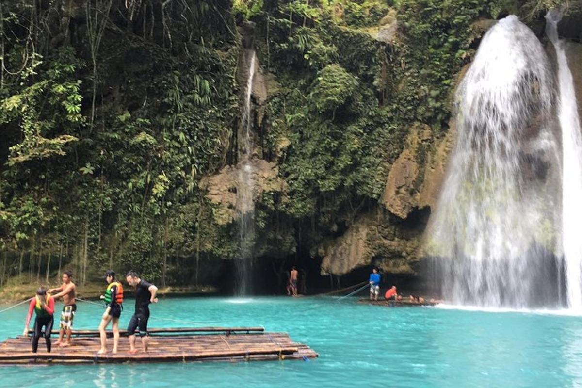 sekumpulan orang berdiri di atas rakit di hadapan air terjun