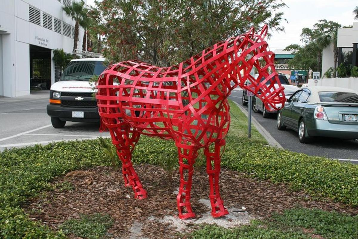 una statua di un cavallo rosso sul ciglio di una strada