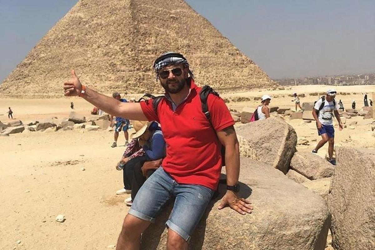 muž sedící na skalách před pyramidami