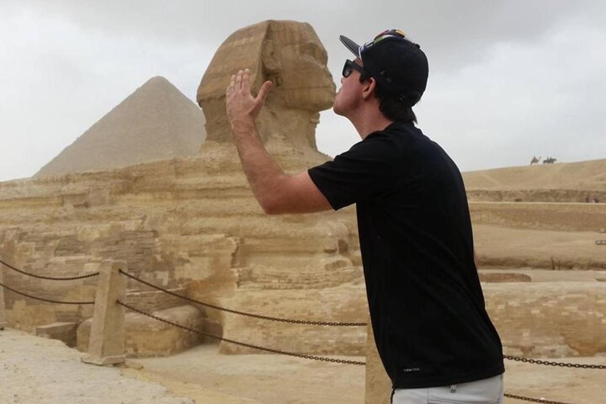 um homem tirando uma foto da esfinge e da pirâmide
