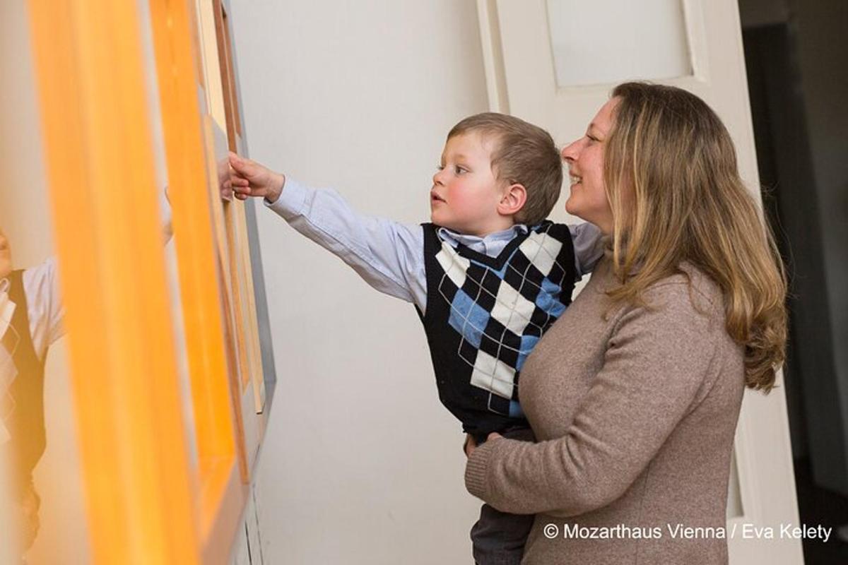 Una mujer y un niño pequeño de pie junto a una pared