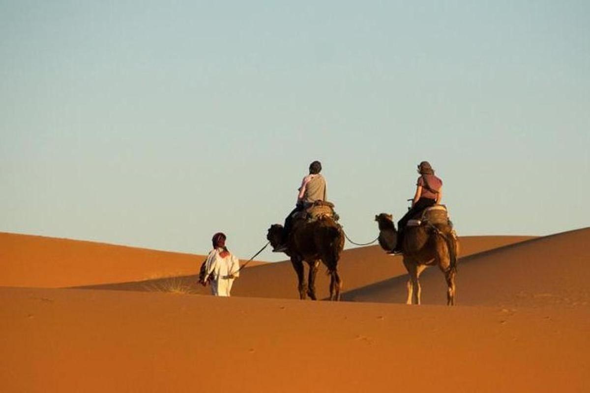 tres personas montando a caballo en el desierto