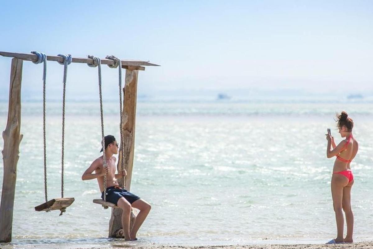 Dos niños sentados en un columpio en la playa