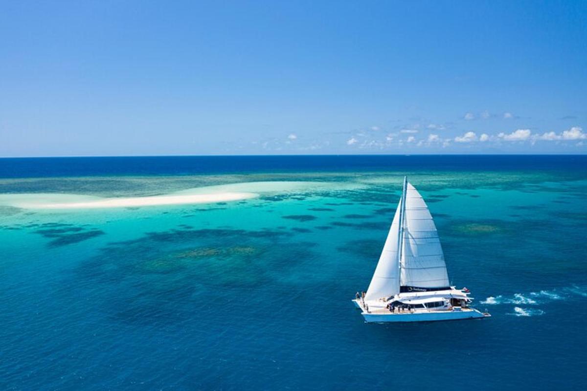 a sailboat in the water with a small island in the background