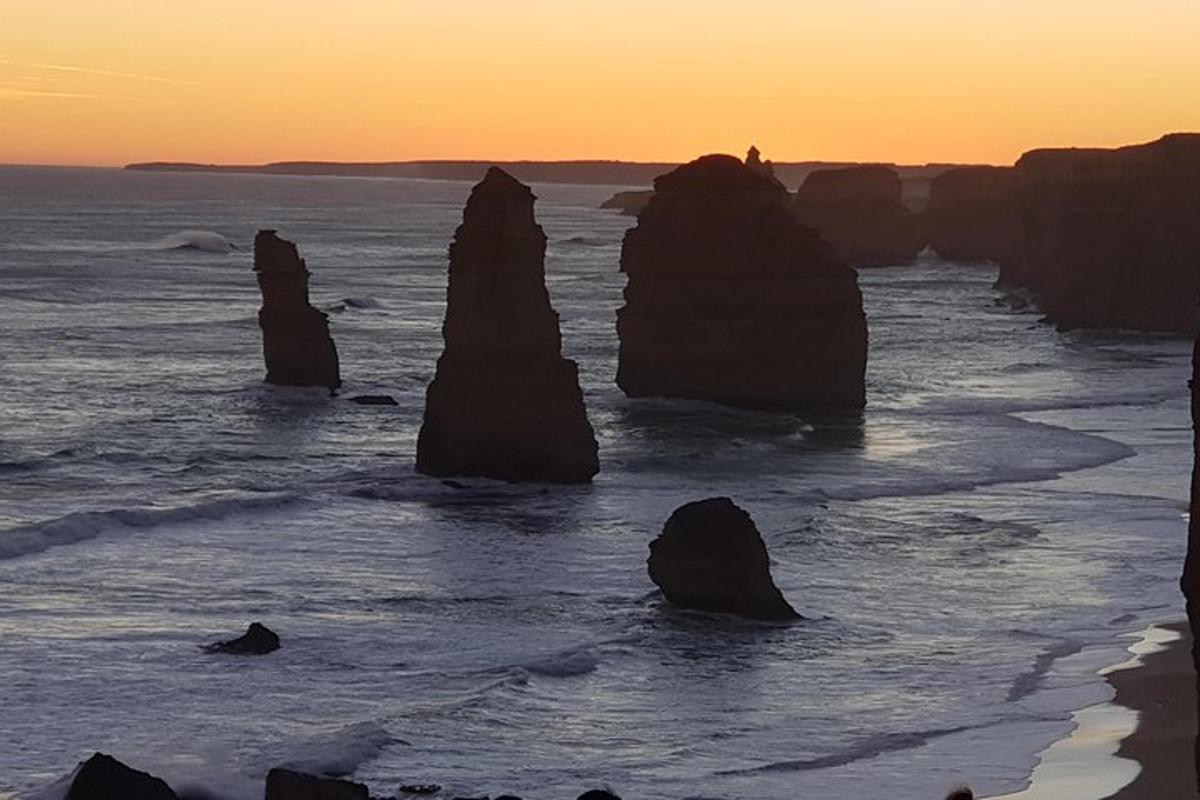 un grup de grans roques a l'oceà a la posta de sol