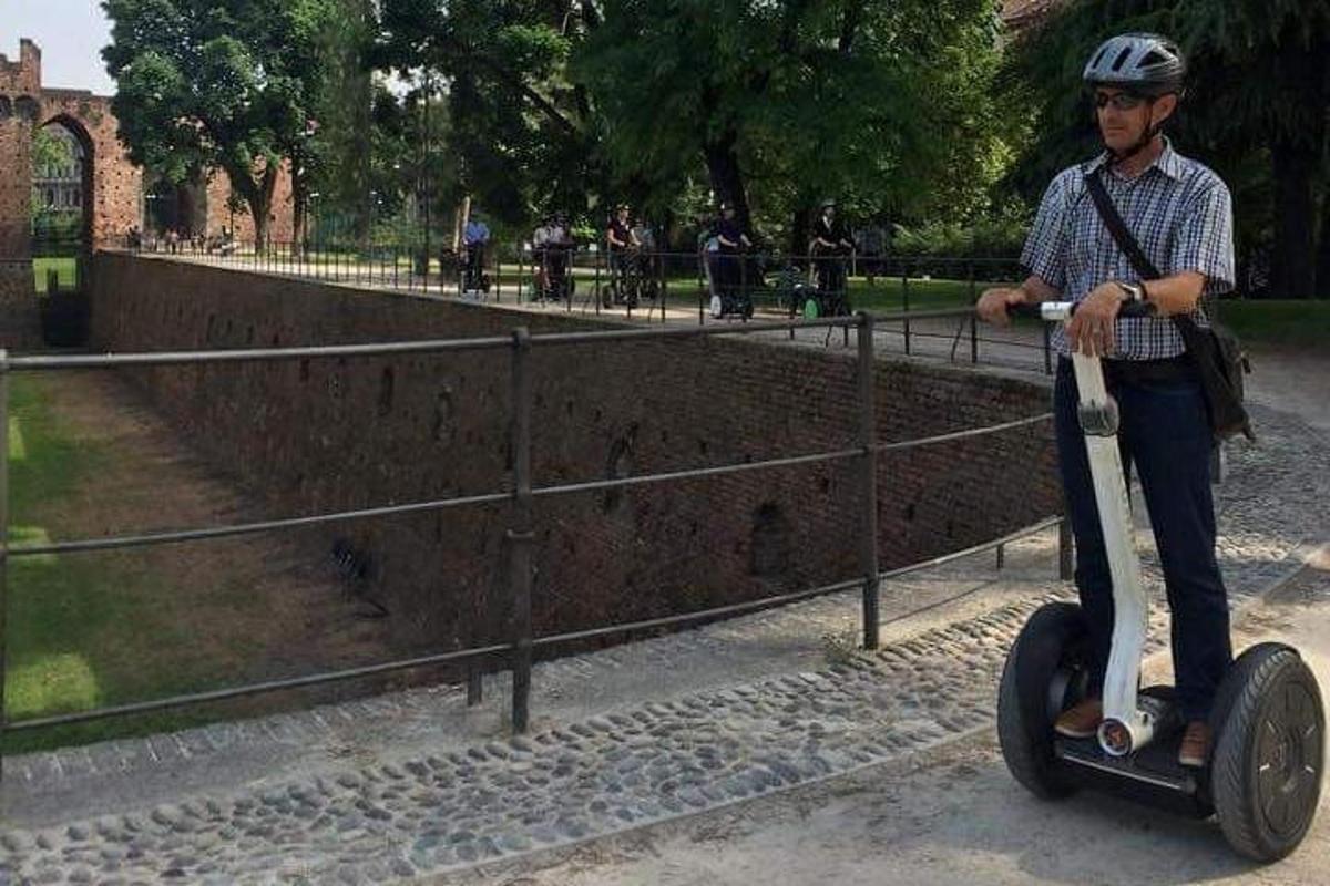 un uomo in sella a uno scooter davanti a una recinzione