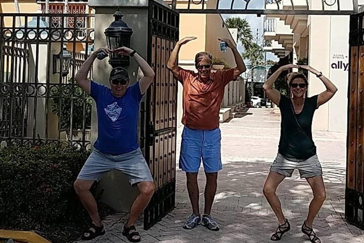 three people standing next to a gate with their arms up