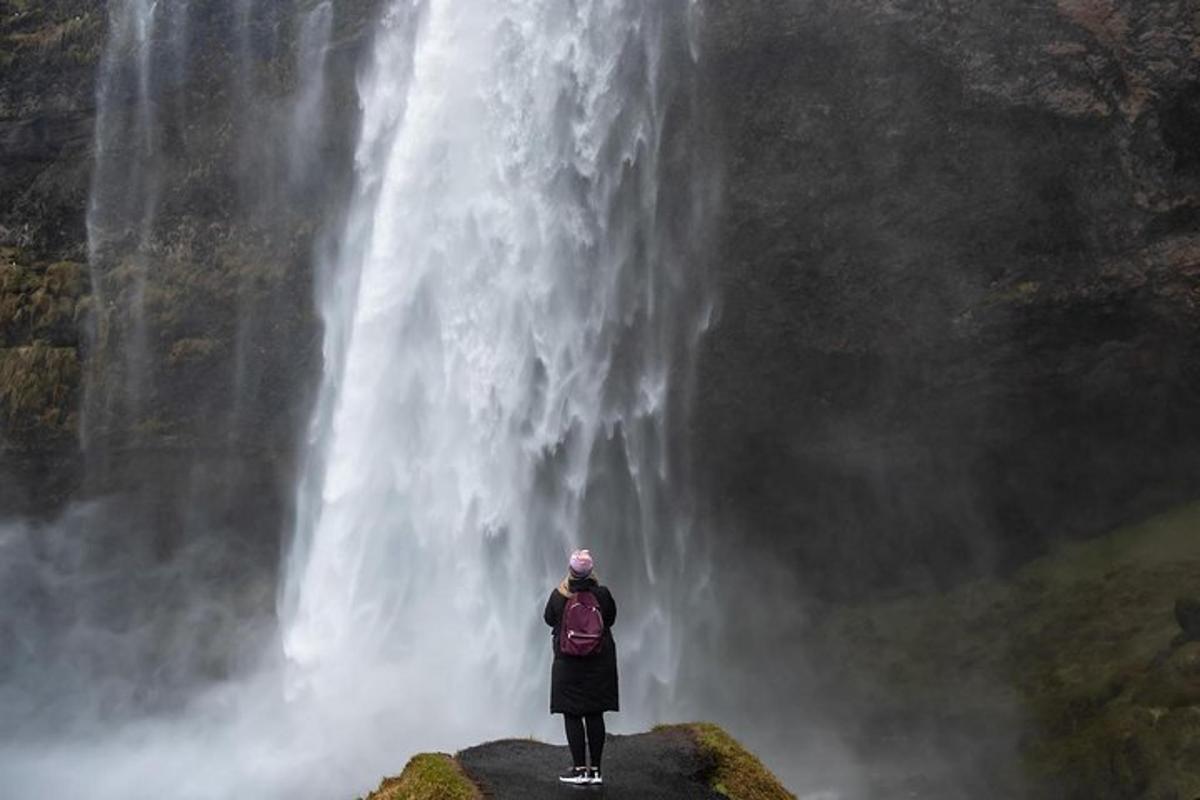 a person standing on a rock in front of a waterfall