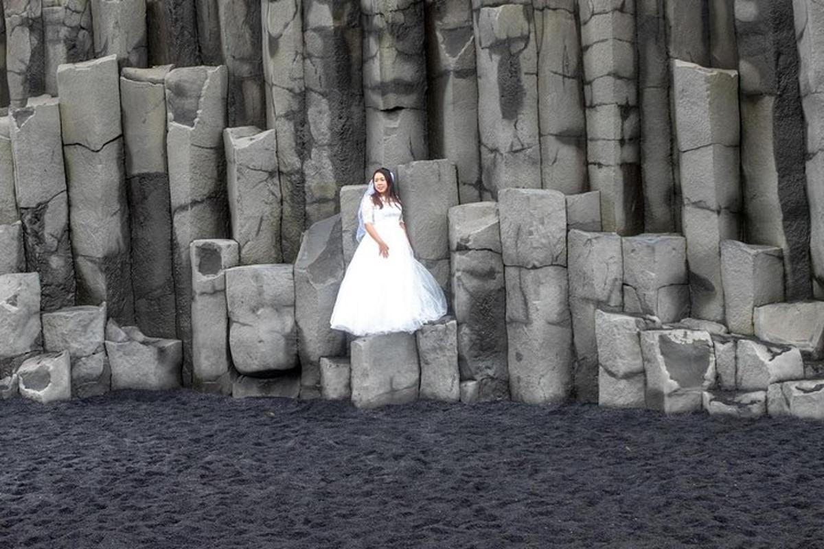 a woman in a white wedding dress standing on a stone wall