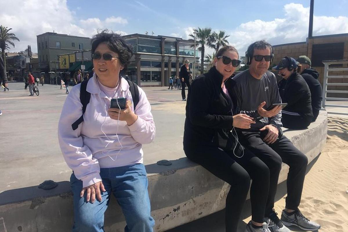 skupina lidí sedících na zdi a dívajících se do svých mobilních telefonů