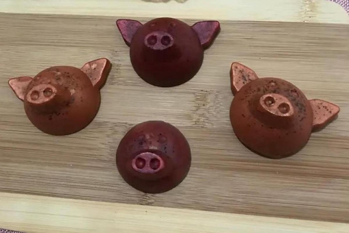 four chocolate pigs on a wooden cutting board