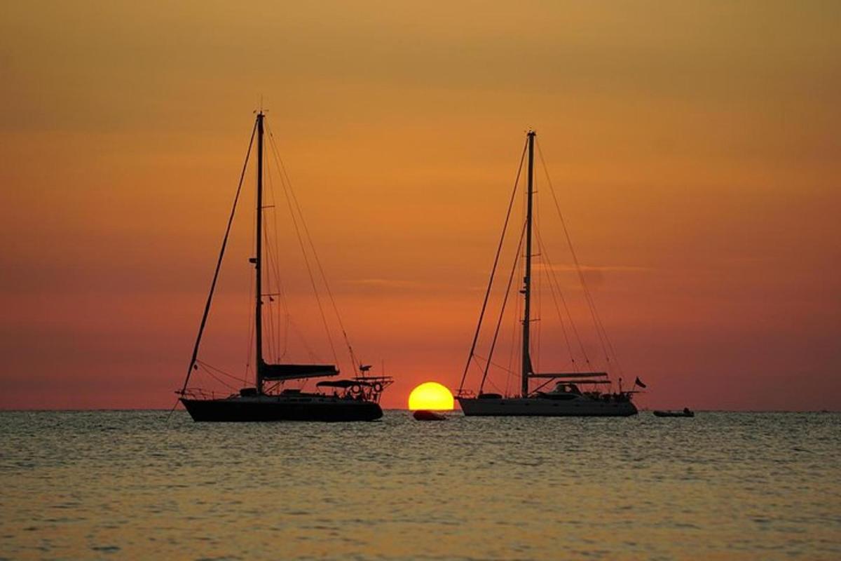 zwei Segelboote im Meer mit dem Sonnenuntergang im Hintergrund
