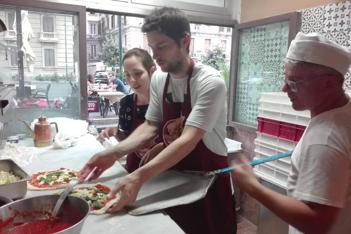 skupina lidí připravujících pizzy v kuchyni