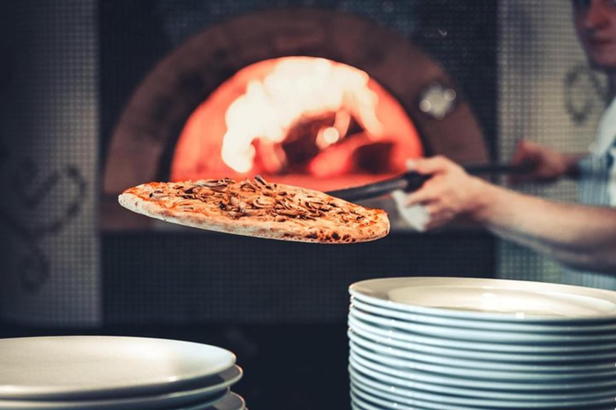 Una pizza en un plato delante de un horno de pizza.