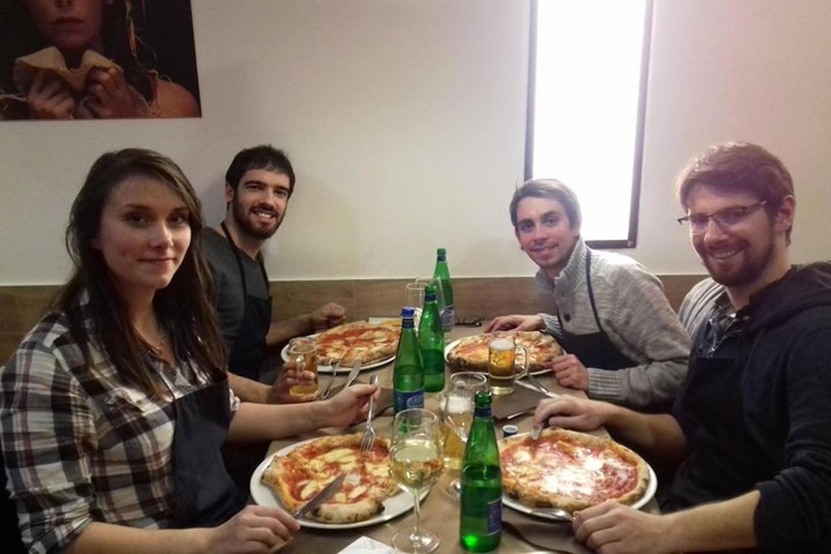 skupina lidí sedících kolem stolu a jedících pizzu