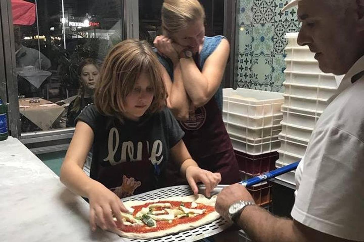 Una niña sentada delante de una pizza