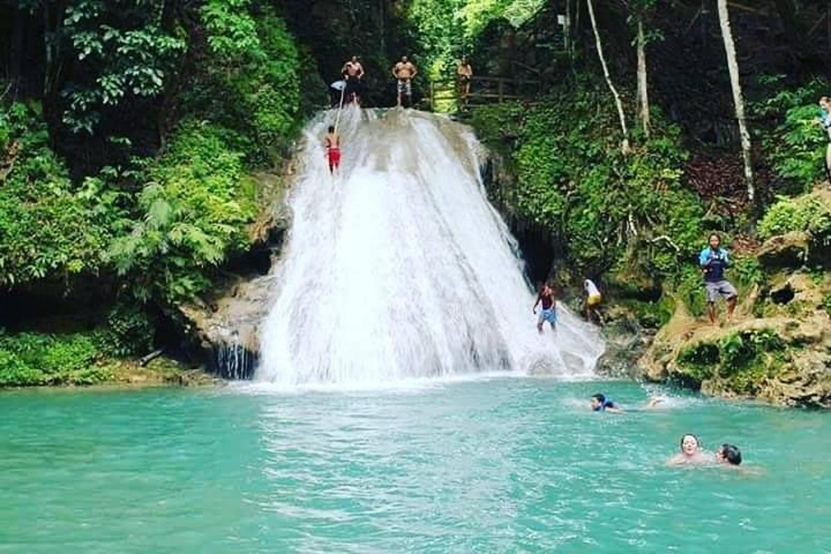 um grupo de pessoas em pé no topo de uma cachoeira