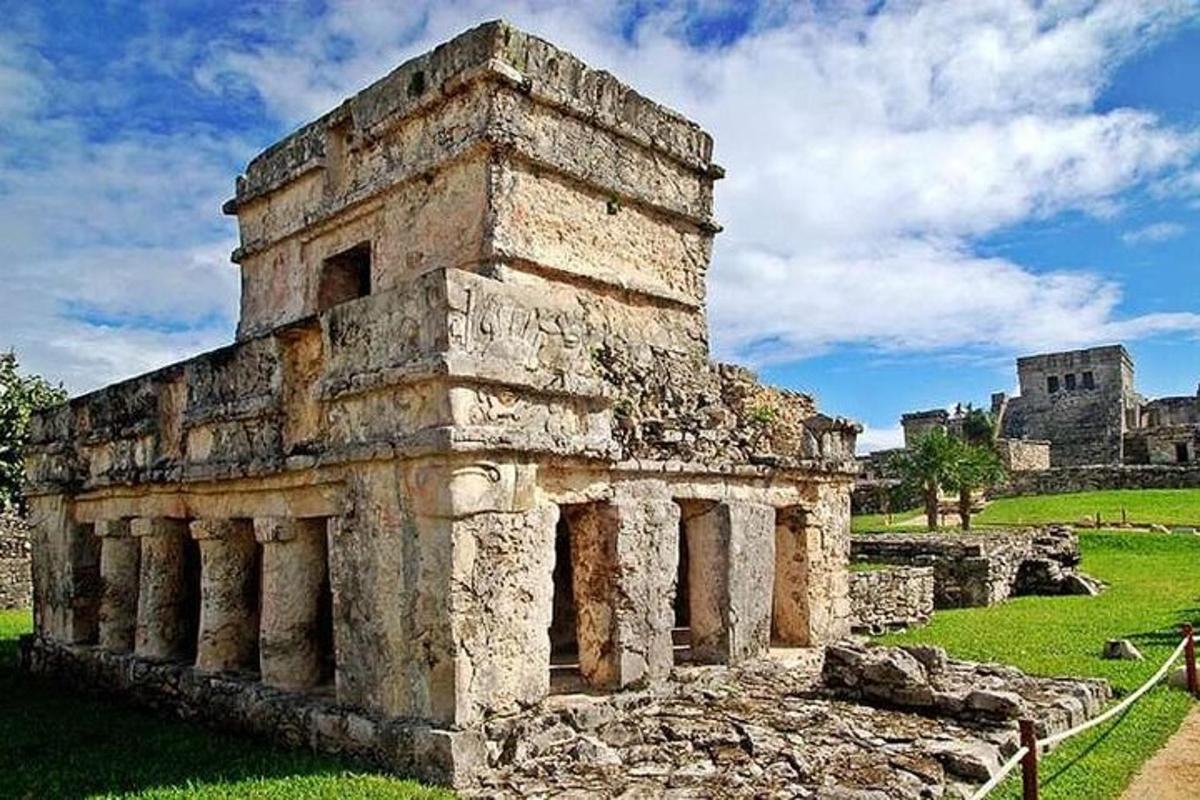 an old building on a field with a castle in the background