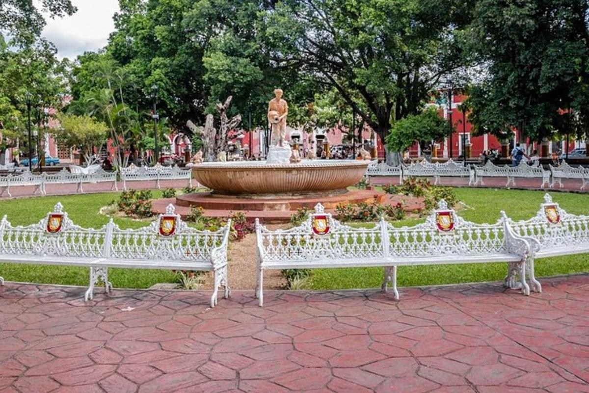Dos bancos blancos en un parque con una fuente.