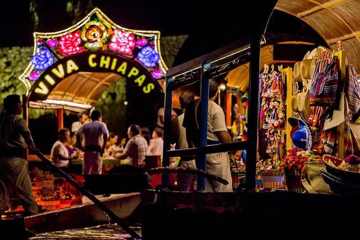 Un grupo de personas de pie en un mercado por la noche.