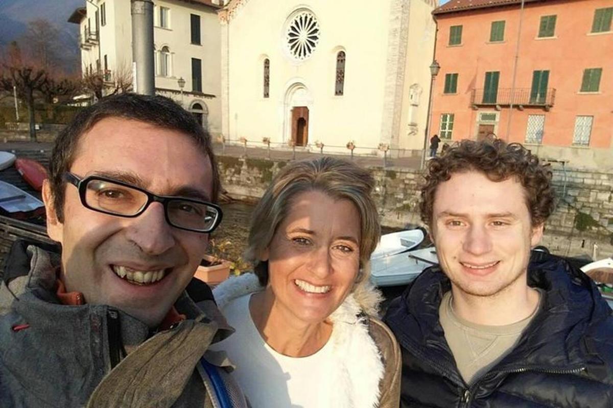 dva moška in ženska pozirajo za sliko pred stavbo